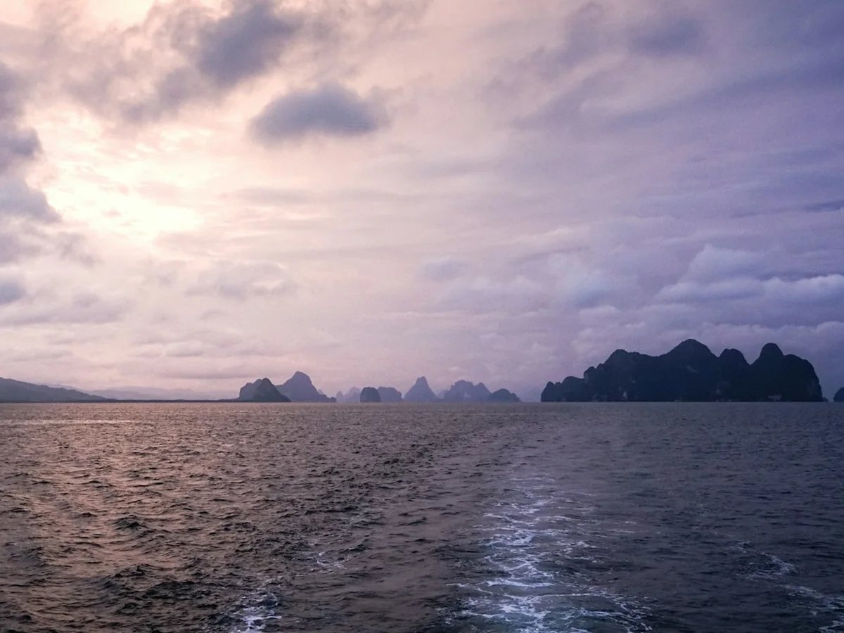 The silhouettes of Phang Nga Bay's karst islands at dusk, representative of the evening return leg